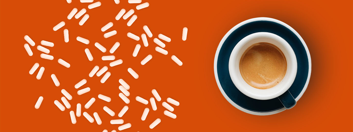 Coffee cup and pills on orange background