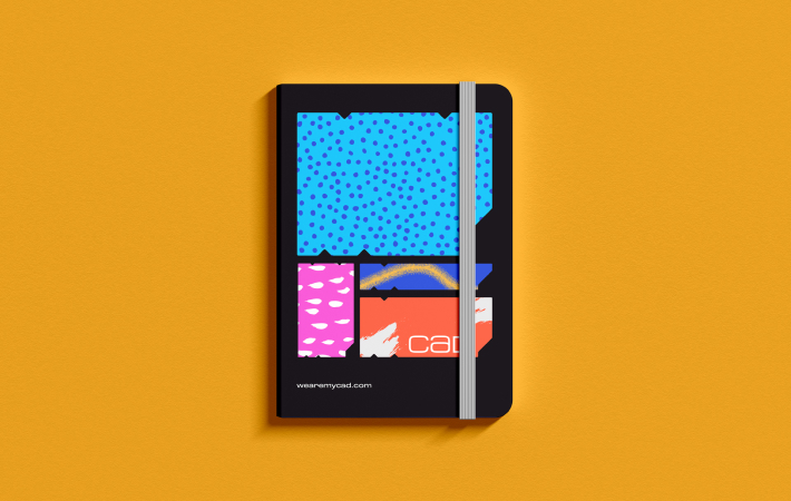 Notebook abstractly branded in MYCAD design on a orange background