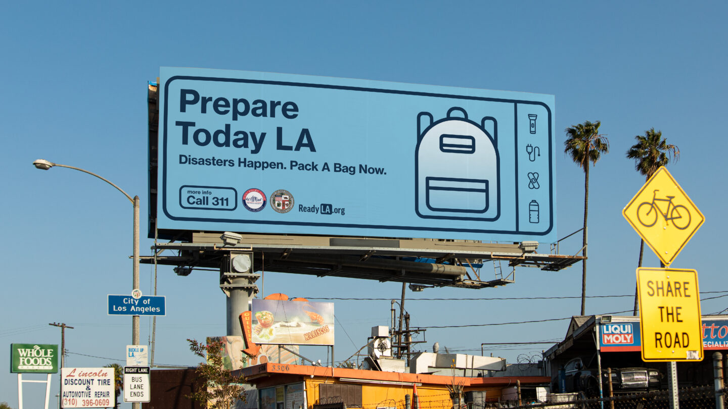 Highway billboard for the City of Los Angeles Emergency Management Department promoting Prepare Today LA, featuring a backpack icon and the message “Disasters Happen. Pack a Bag Now.”